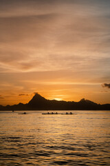 Fototapeta premium Atardecer isla de moorea en polynesia francesa y canoas remando horizonte 