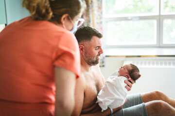 Fototapeta premium New born baby boy resting in father arms with nurse