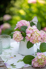 Tavolo decorato con un vaso di latta con fiori di ortensia di colore rosa