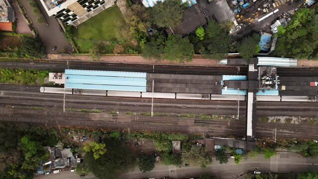 Aerial footage of Mumbai local train. Drone shot of local moving to Mumbai City. Urban train aerial video. Indian commuter train in city. Topdown view of railway train in India