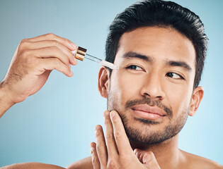 Face, beauty and antiaging oil with a man in studio on a blue background for skincare or grooming....