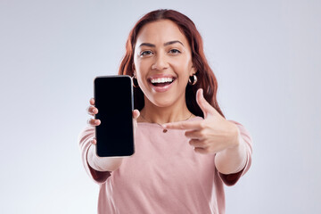 Happy woman is pointing at phone screen, mockup and marketing, mobile app ads on white background. Website promo, advertising and female ambassador in portrait with social media branding in studio - obrazy, fototapety, plakaty