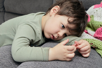 young boy playing with a hairclip on the couch at home