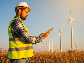 Engineer using a tablet to adjusts the power and rotation speed of each turbine in the wind park....