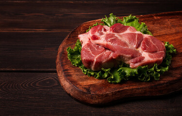 raw pork steak, two pieces, on a wooden background,