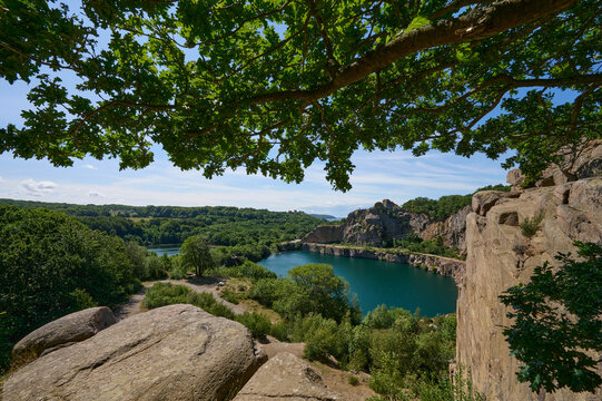 Blick auf den von Granitfelsen umgebenen k&uuml;nstlichen dunkelgr&uuml;n-blauen See Opals&oslash;en im Norden der d&auml;nischen Ostseeinsel Bornholm an einem Sommertag
