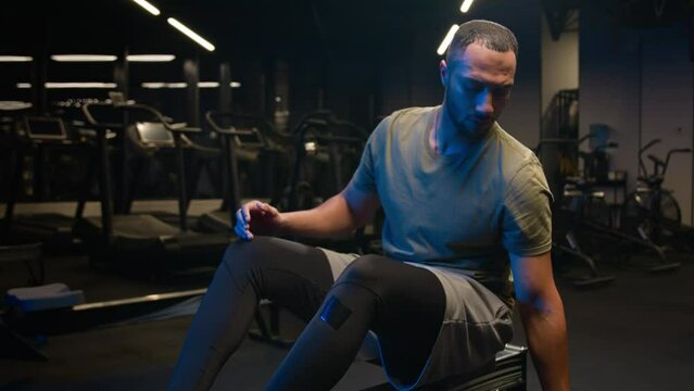 African American man mobile phone scrolling smartphone finish chatting sportsman male doing sport exercise with equipment in gym workout biceps triceps push down sitting horizontal pull block back