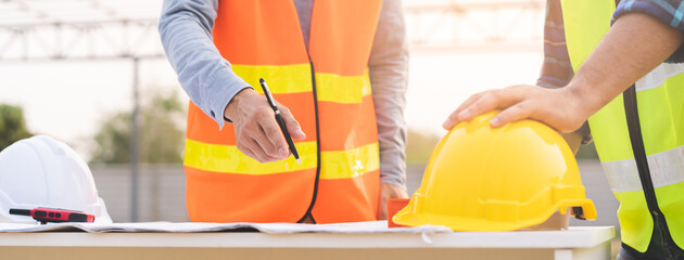 Builder team, hand of two asian young engineer, architect man, male discussing construction, follow project to build  industrial plan on table at site outdoor. Engineering worker, teamwork people.