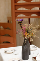 Beautiful flowers decorated on luxury elegant table setting dinner in a restaurant with wooden spiral staircase in soft focus