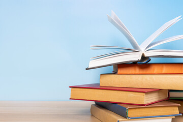 Composition with vintage old hardback books, diary and open book whith old pages on wooden table and blue background. Books stacking. Back to school. Copy Space. Education background.