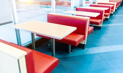 Empty fastfood restaurant interior with red chairs and table in a row