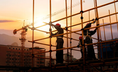 Group of construction workers working on scaffolding - obrazy, fototapety, plakaty