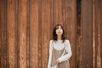 Fototapeta premium 木造の塀を背景に立つ女性のポートレート