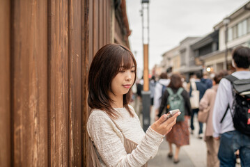 川越の観光地の通りでスマートフォンを見る女性