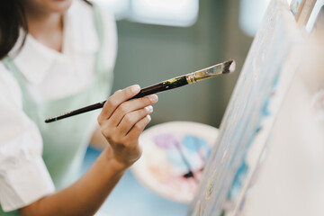 Close-up of female artist painting on canvas with brush Young painter working on the floor of her art studio creative young woman painting with oil paints creative concept