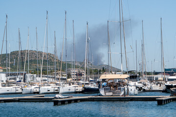 Obraz premium Waldbrand bei Sibenik gesehen durch einen Hafen mit Segelbooten im Vordergrund