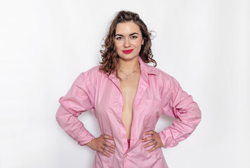 Happy sexy brunette smiling mysteriously. A pink shirt is draped over her bare chest.