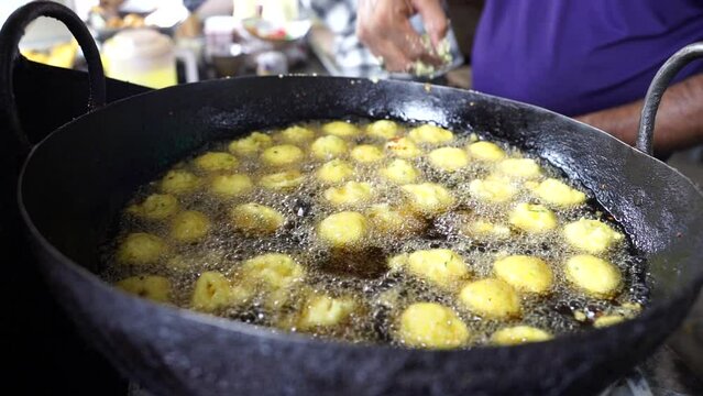Close-up sense of Making Frying Fritters Indian Street food which is also known various name like Moong Dal Pakoda, Moong Dal Bhajiya, Moong Dal Vada, Pakoda, Bhajiya, Aloo Pakora, bhajiya, etc. 
