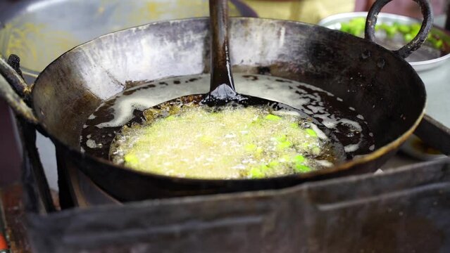 Close-up sense of Making Frying Fritters Indian Street food which is also known Aloo Pakora, bhajiya, etc.