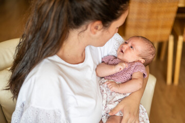 Newborn In Arms Of Young Mother. Keen. Close-up of a little baby Looking at the mother.