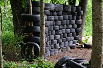 wall made of used tires in forest between tree trunks