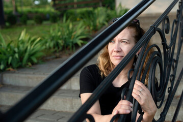 A woman sits on steps of church and looks hopefully at the sky, the woman is afraid to enter...