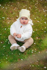 Cute baby toddler crawling on grass outdoors in a plush jacket