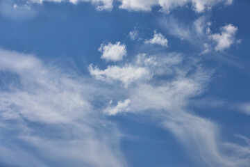 Naklejka na ściany i meble Cloudy blue sky background with white swirling clouds.