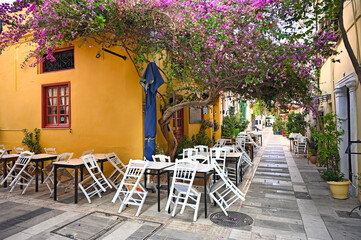 Fototapeta na wymiar Restaurant and houses in the narrow streets of Nafplion town with Bougainvillea flowers