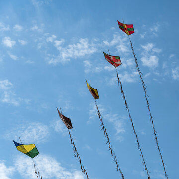 Colorful handmade paper kites or Pipas (Brazil) flying in the blue sky with white clouds. Peruibe, Brazil.