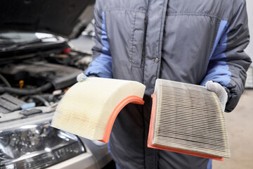New and old dirty automotive engine air filter in the hands of an auto mechanic. Auto repair...