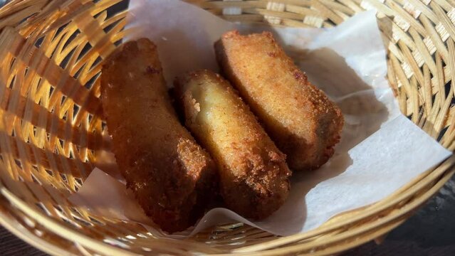 Chef pours fried banana pieces with hot cane sugar oil on a hot frying pan in slow motion. High quality 4k footage
