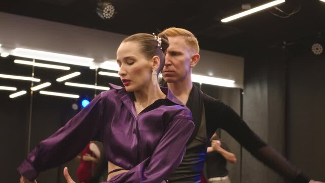 Medium slowmo of sensual Caucasian couple in elegant outfits performing beautiful Latina dance during dance class in ballroom