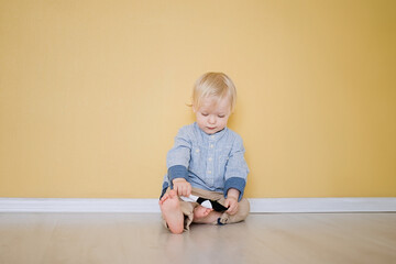 Naklejka premium Portrait of a two years old child sitting on the floor. Pretty little boy at home 
