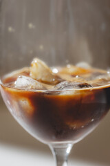 Process professional Iced espresso pouring from coffee machine to wineglass with ice