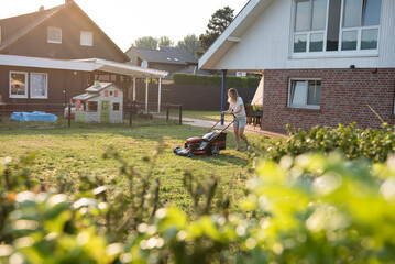 Fototapeta na wymiar woman mowing lawn in garden