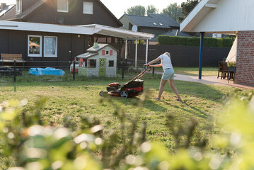 Obraz na płótnie Canvas woman mowing lawn in garden