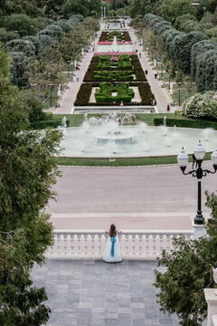 Distant girl in dress on terrace with fountain park