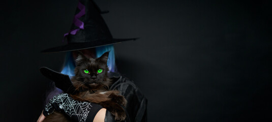 Witch with blue and violet hair, black hat with violet ribbon and long black nails is holding cat on her hands.