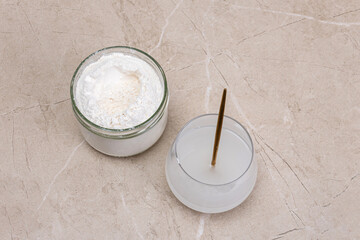 Glass of water and a jar of collagen goodnesson a marble beige background.
