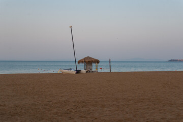 View of the catamaran and milking from the thatched roof at sunrise on the beach by the sea