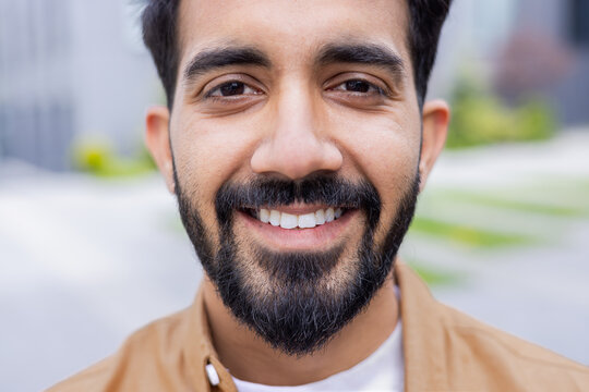 Close up photo portrait of young Hindu student, man smiling and looking at camera, businessman outside office building wearing shirt.