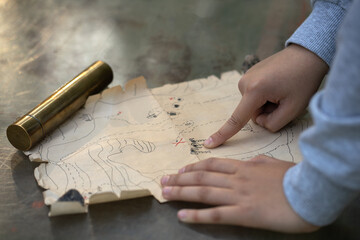 The child points to the designation of the place with the buried treasure on the pirate map. A...
