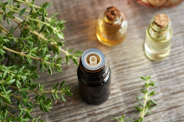 A dropper bottle of thyme essential oil with fresh thyme