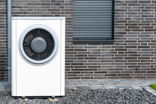 Au&szlig;enmodul einer modernen W&auml;rmepumpeheizung im steinernen Vorgarten eines Wohnhauses