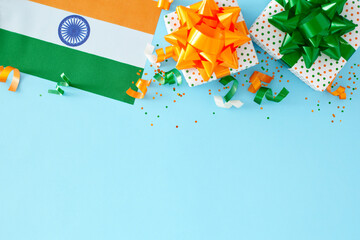 India Republic Day gift concept. Top-down view of gift boxes in national colors, indian flag, sparkles on pastel blue background with empty space for ads or message