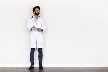 Cheerful indian young doctor holding medical folder, white background