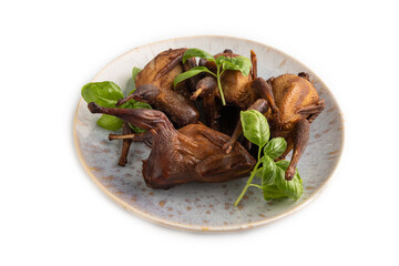 Fototapeta na wymiar Smoked quails on a ceramic plate isolated on white background. Side view
