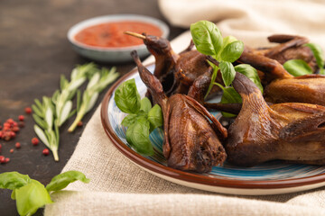 Smoked quails on a ceramic plate on a black concrete background. Side view, selective focus