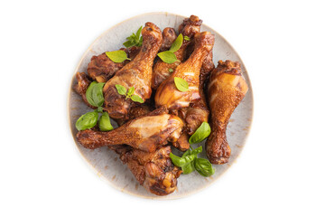 Smoked chicken legs on a ceramic plate isolated on white background. Top view, close up.
